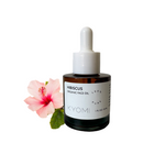 Bottle of KYOMI hibiscus organic face oil with a pink flower on a white background