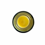 Small jar of yellow cream on a white background