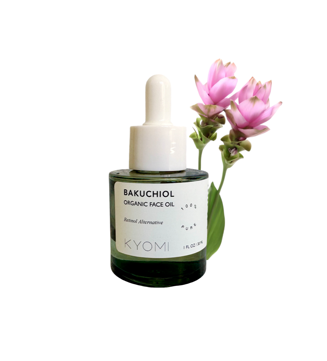 Bottle of KYOMI Bakuchiol Organic Face Oil with a pink flower on a white background