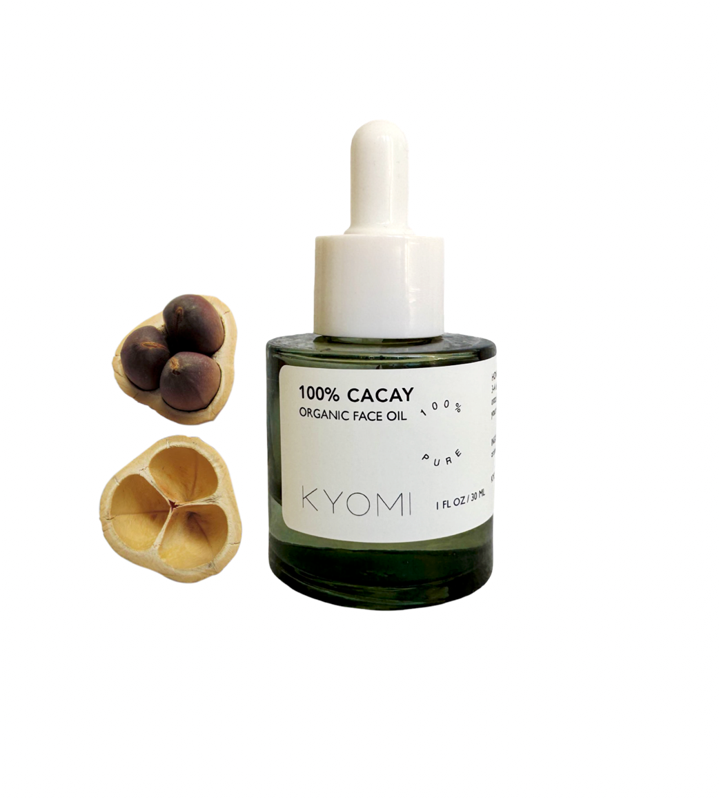 Bottle of KYOMI 100% Cacay Organic Face Oil with wooden applicators on a white background